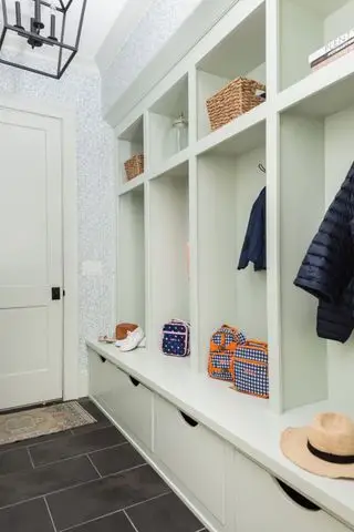mudroom com armários brancos e piso escuro
