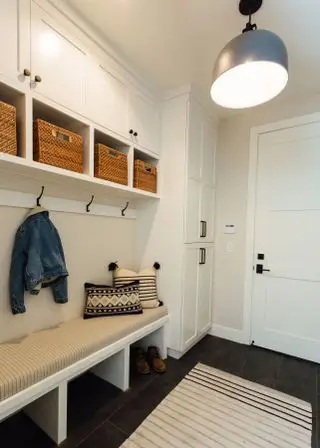 mudroom com armários brancos e piso escuro
