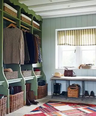 Um mudroom com uma estante verde aberta dividida em seções pessoais e cestos de tecido para botas