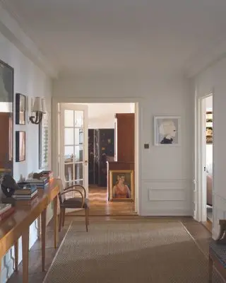 Idée de couloir peint en blanc avec tapis en jute, œuvres d'art et console en bois du milieu du siècle.