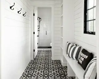 L'entrée d'une salle de bains avec piscine avec carrelage à motifs noirs et blancs et murs à feuillures blancs.