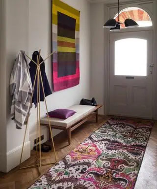 Smale hall ideer med rosa og lilla mønstret løper og kunstverk.