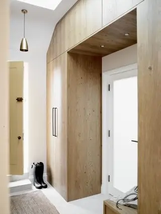 couloir/entrée avec rangements intégrés en bois, sol blanc, tapis, suspension, murs blancs