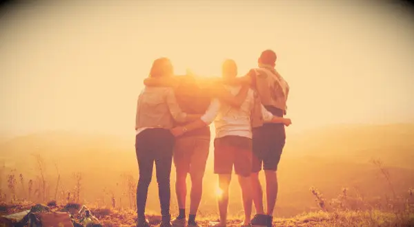 Friends hugging and watching a sunset.