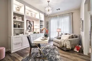 home office con scrivania indipendente, scaffali e armadietti espositivi, poltrona e lampada a sospensione