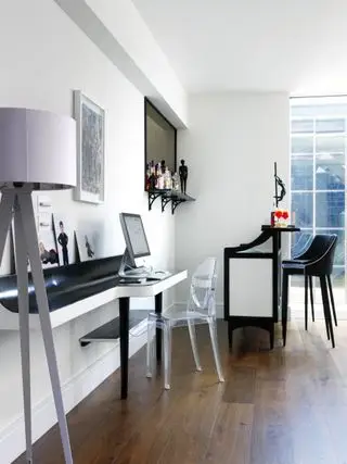 Sous-sol avec murs blancs, plancher de bois, bureau suspendu et bar avec tabourets de bar