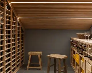 Cave à vin au sous-sol avec rangement pour le bois, tabourets en bois et bandes lumineuses au plafond