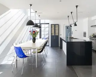 Cuisine-salle à manger au sous-sol avec îlot, table et chaises et portes donnant sur l'extérieur avec carrelage gris et murs blancs