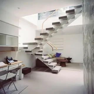 Escalier à marche ouverte avec balustrade en verre menant au sous-sol au décor neutre avec coin salon et bureau