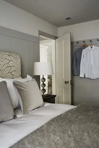 Chambre avec murs lambrissés en gris et plafond gris et tringle pour vêtements