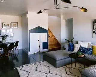 Rénovation du sous-sol avec canapé sectionnel, table d'appoint et tapis, table et chaises à manger, maisonnette pour enfants, murs blancs et sol sombre