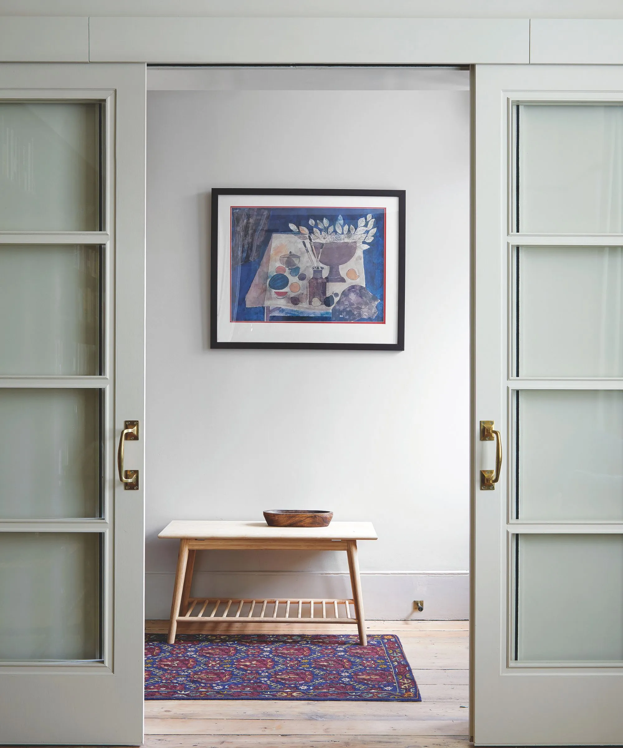 Minimálna chodba s moderným umením na nástenných posuvných dverách drevená konzola a červený a modrý perzský koberec' loading='lazy' title=