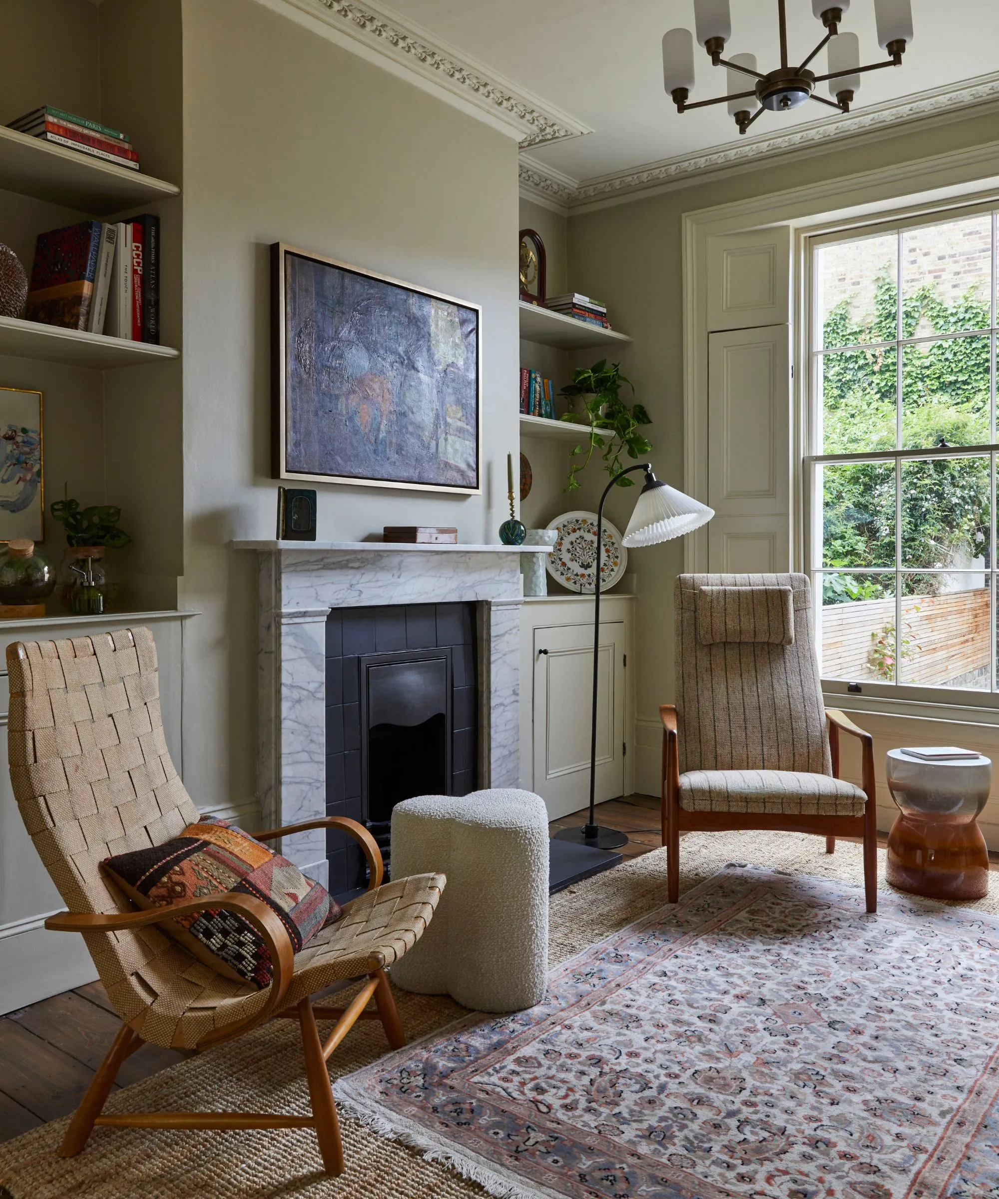 Obývacia izba s béžovými stenami, veľkými arkierovými oknami s mramorovým krbom, policami na knihy a perzským kobercom' loading='lazy' title=