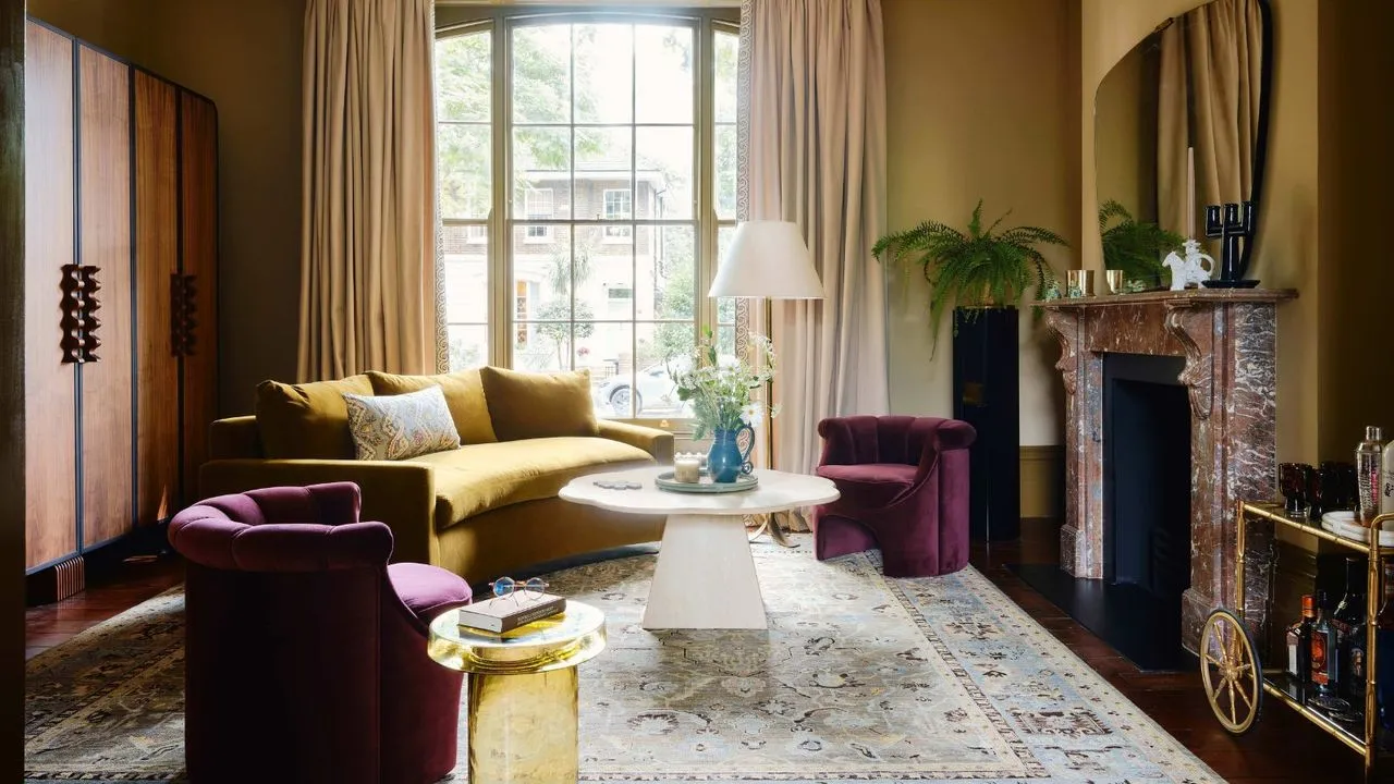 okkermalet storslået stue med en antik rød marmorpejs et stort vindue gul buet sofa rundt hvidt sofabord og lilla buede lænestole' loading='lazy' title=