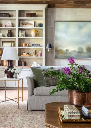 Idées de décoration de ferme, salon confortable avec tapis à motifs, canapé gris, table basse en bois, étagères blanches, grandes œuvres d'art