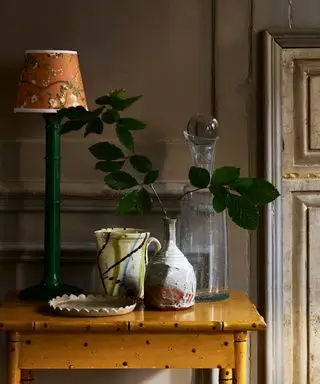 Table d'appoint peinte en jaune ocre avec lampe de table verte, abat-jour décoratif jaune et récipients en céramique