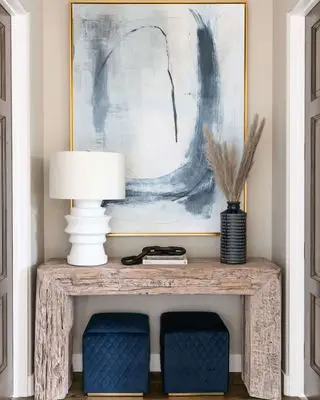 Útulný vchod s dřevěným konzolovým stolem, uměleckým dílem, zelení a stolní lampou