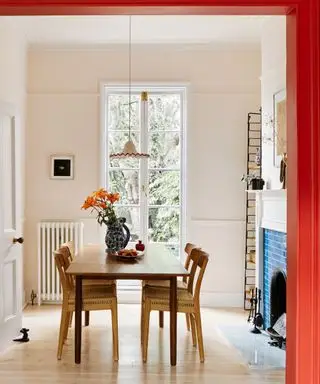 couleurs qui vont avec le rouge, salle à manger avec murs blush, plafond blanc, boiseries rouges autour de l'encadrement de la porte, cheminée avec carrelage bleu, parquet en bois clair