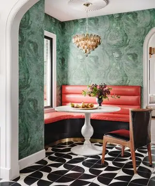 couleurs qui vont avec le rouge, espace salle à manger avec banquette rouge, sol carrelé noir et blanc, table ronde blanche, chaise de salle à manger, lustre, papier peint style marbre vert émeraude
