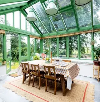 zimní zahrada se zeleně malovanými okenními rámy a jídelním stolem