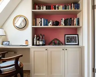 Heimbüro mit roten Wänden, cremefarbenen Schränken und Regalen