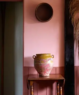 Roter Eingangsbereich mit rosa gestrichenen Wänden und Urne auf dem Tisch