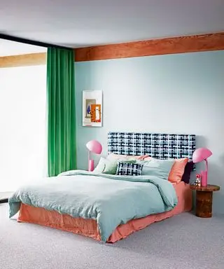 Moderne soveværelse med dobbeltseng med grønt sengetøj, lyserøde sengelamper og grønne gardiner.