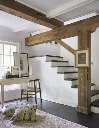 Sous-sol avec fenêtre, poutres, parquet en bois foncé, escalier en bas, bureau et chaise