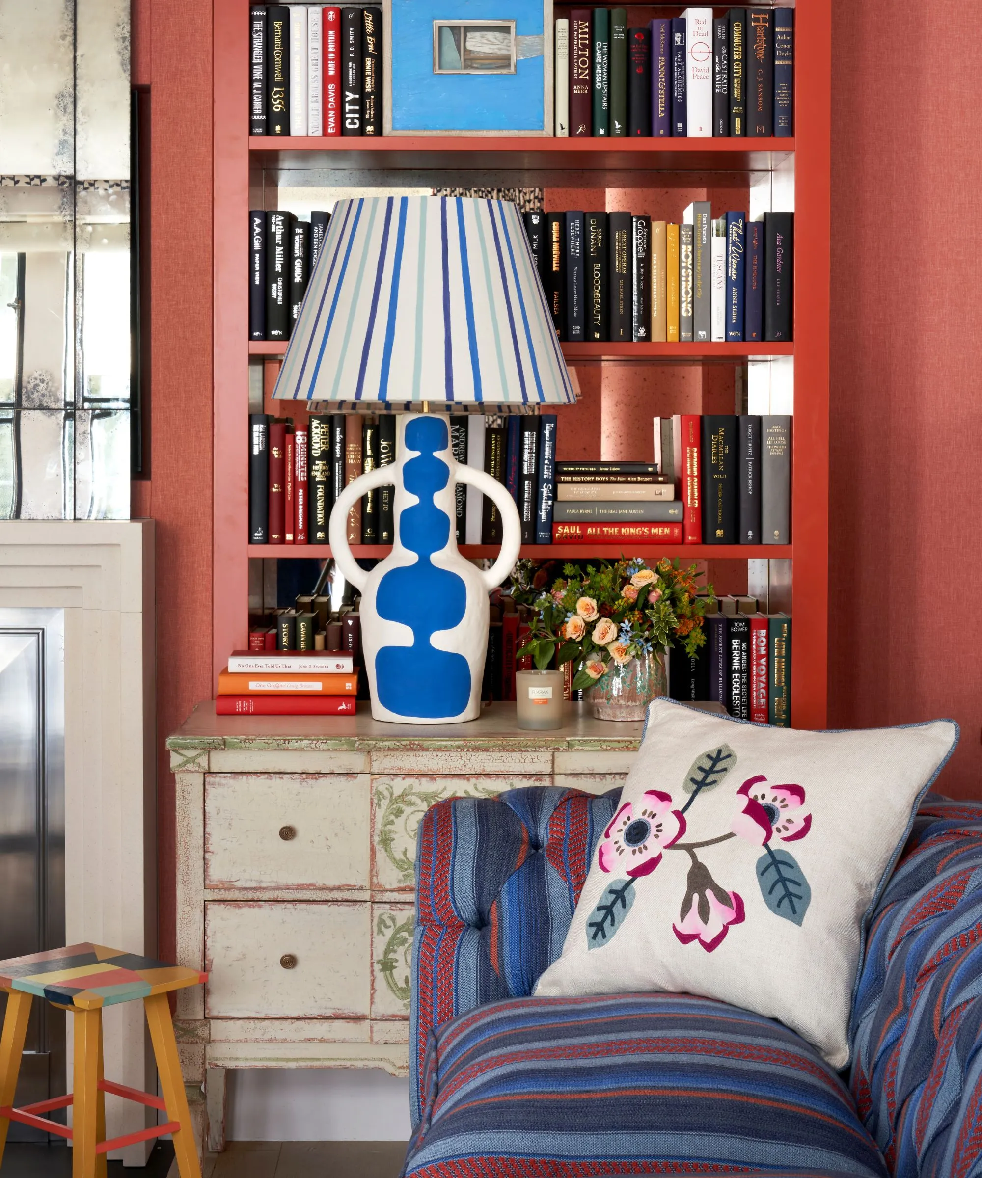 czerwona wnęka w salonie z wbudowanym regałem ozdobionym lampą w niebiesko-białe paski' loading='lazy' title=