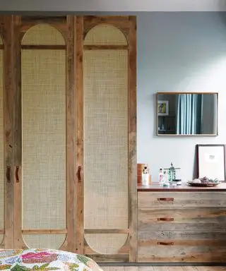 Almacenamiento en dormitorio alto con azotes en las puertas y un juego de cajones.