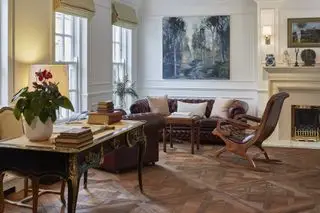 Parquet dans le salon traditionnel avec fauteuil canapé en cuir et bureau