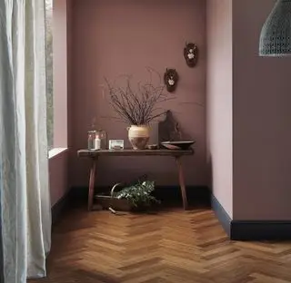 Parquet en bambou posé à chevrons dans un couloir avec des murs roses.webp
