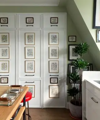 나무 테이블이 있는 녹색 페인트 주방과 예술 작품이 있는 패널 저장 도어