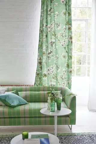 녹색 꽃무늬 커튼, 녹색 체크 소파, 사이드 테이블, 검정색 및 녹색 러그가 있는 흰색 및 녹색 거실