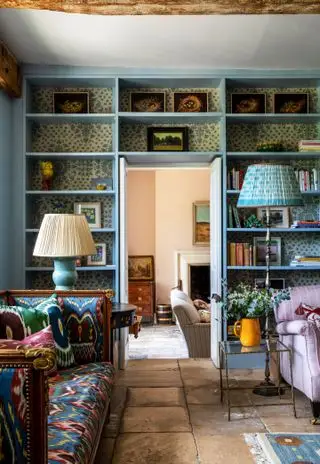 문 주변에 선반이 있는 거실, 소파, 안락의자, 석조 바닥