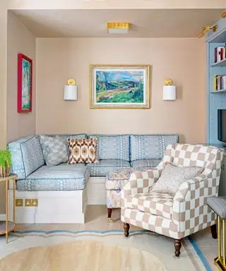 Petit salon avec canapé à motifs bleus, fauteuil à carreaux, œuvres d'art et appliques murales sur les murs, tapis coloré