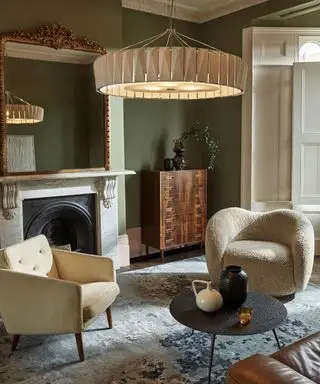 Sala de estar aconchegante com área de estar, pendente grande e baixo, paredes pintadas de verde, lareira, móveis neutros e naturais