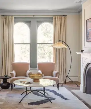 Sala de estar moderna com janelas em arco, poltronas combinando, luminária de chão curvilínea, tapete e lareira