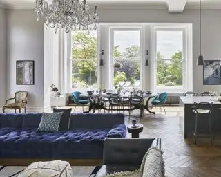 Une idée de salle à manger avec une grande cuisine ouverte, un salon et une salle à manger avec de grandes fenêtres et un canapé et des chaises bleues