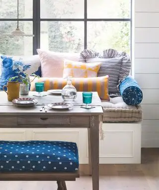 Salle à manger avec banquette de fenêtre et verrerie colorée