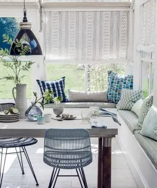 Salle à manger blanche avec siège de fenêtre et table en bois