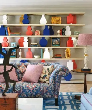 Grande étagère décorée de livres et d'ornements coordonnés, canapé à motifs, table d'appoint, lampe de table