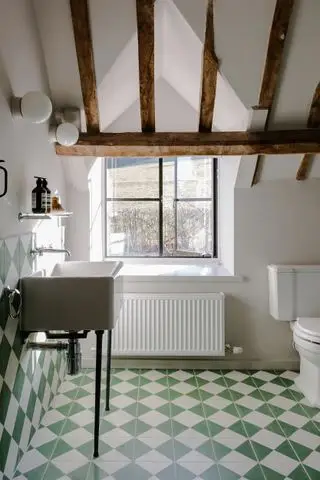 Une salle de bains verte et blanche avec du carrelage vert et blanc au sol et aux murs dans un style maison de campagne