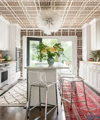 茶色、茶色と白のキッチン、茶色とタイル張りの壁と天井、白いユニット、白いキッチンアイランド、バースツール、堅木張りの床の敷物に合う色