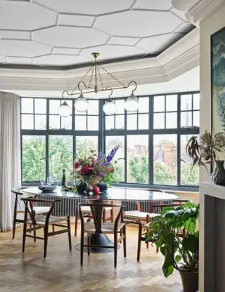 Comedor con artesonado pintado de blanco y suelo de madera.