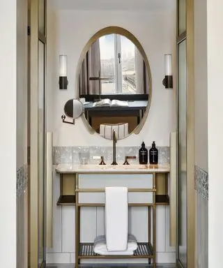 Badezimmerwaschbecken mit Armaturen aus dunklem Messing und ovalem Spiegel