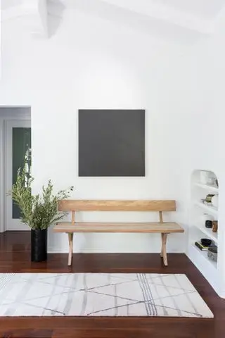 כניסה לבנה עם שטיח, רצפת עץ וספסל עץ