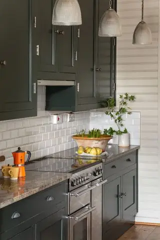 cozinha verde escura com azulejos de metrô brancos e parede shiplap pintada de creme