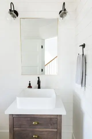 banheiro pintado de branco com paredes brancas shiplap luminárias e acessórios pretos e espelho de latão