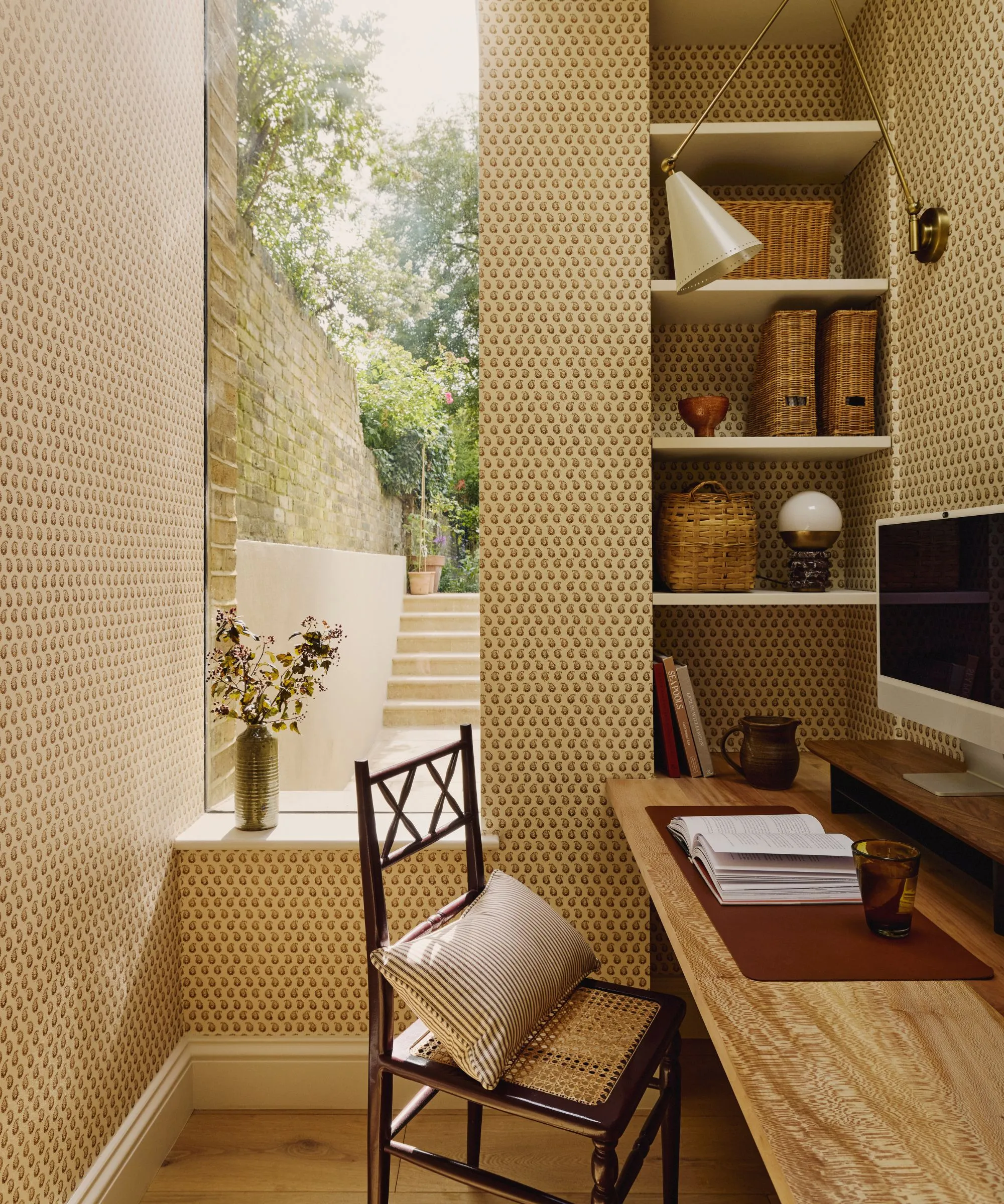 kancelársky priestor so vzorovanými tapetovými vstavanými policami s úložným priestorom vo vnútri políc a stolom s knihou a počítačom navrchu' loading='lazy' title=